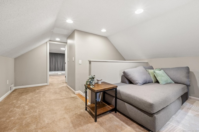 sitting room featuring light colored carpet, vaulted ceiling, and a textured ceiling