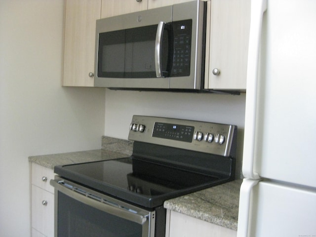 kitchen with appliances with stainless steel finishes, light stone countertops, and light brown cabinets