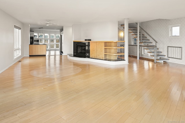 unfurnished living room with ceiling fan, plenty of natural light, and light wood-type flooring