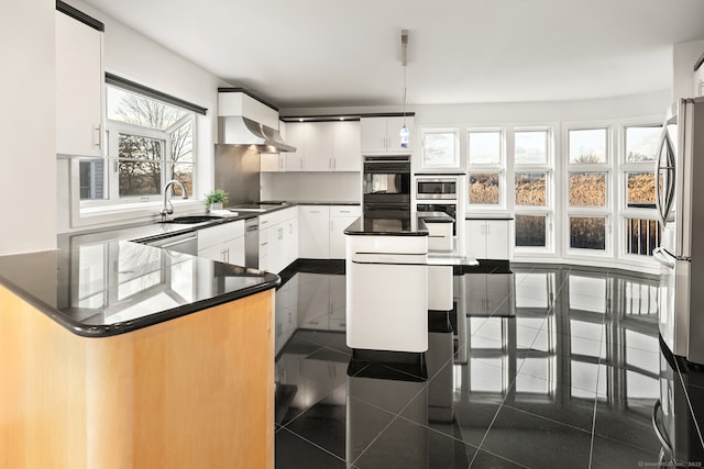 kitchen with sink, white cabinetry, black appliances, a kitchen island, and decorative light fixtures