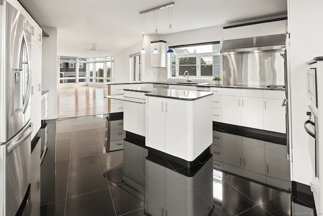 kitchen featuring pendant lighting, sink, stainless steel fridge, white cabinets, and a kitchen island