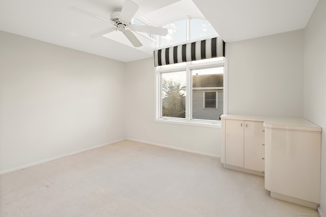 spare room with a wealth of natural light, light colored carpet, and ceiling fan