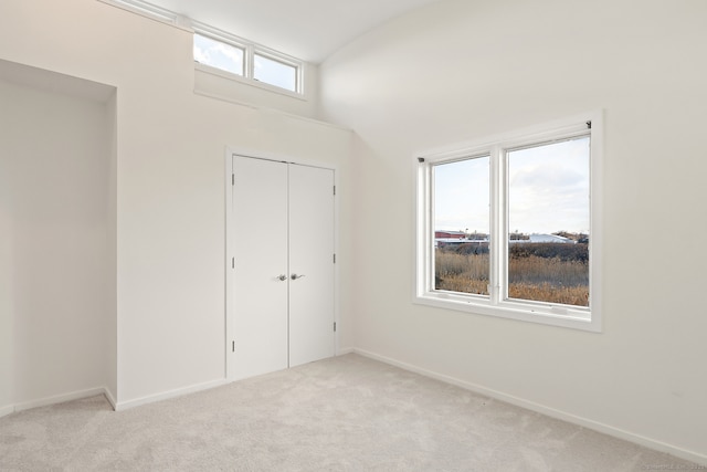 interior space with vaulted ceiling, light colored carpet, and a closet