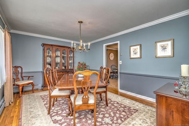 dining space featuring crown molding, a chandelier, light hardwood / wood-style floors, and a baseboard heating unit