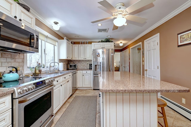 kitchen with a baseboard radiator, sink, a breakfast bar area, a center island, and stainless steel appliances