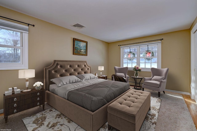 bedroom with multiple windows, light wood-type flooring, and baseboard heating