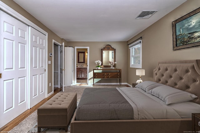 bedroom with ensuite bathroom and light hardwood / wood-style floors