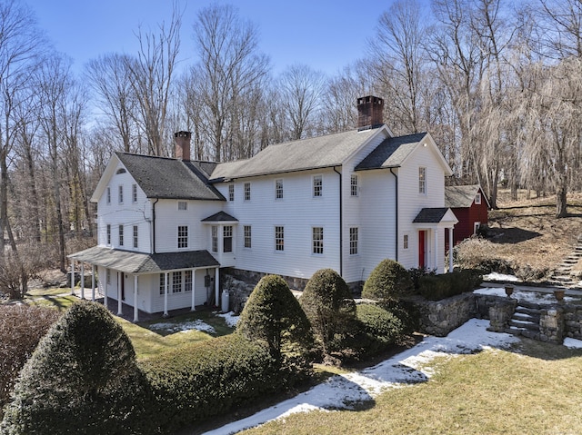 rear view of property with a yard, a shingled roof, and a chimney