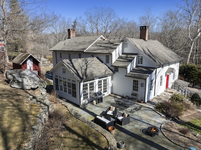 rear view of property with a chimney, a fire pit, and a patio