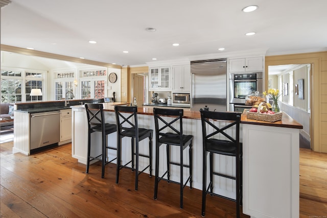 247 Mill Rd, New Canaan, CT 06840 - kitchen with built in appliances, butcher block counters, a spacious island, a breakfast bar area, and ornamental molding