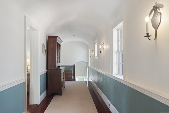 corridor with vaulted ceiling and baseboards