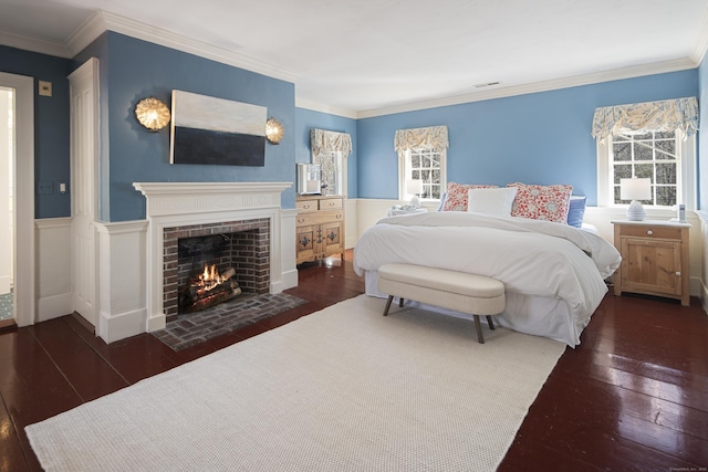 bedroom featuring ornamental molding, a wainscoted wall, a fireplace, and hardwood / wood-style floors