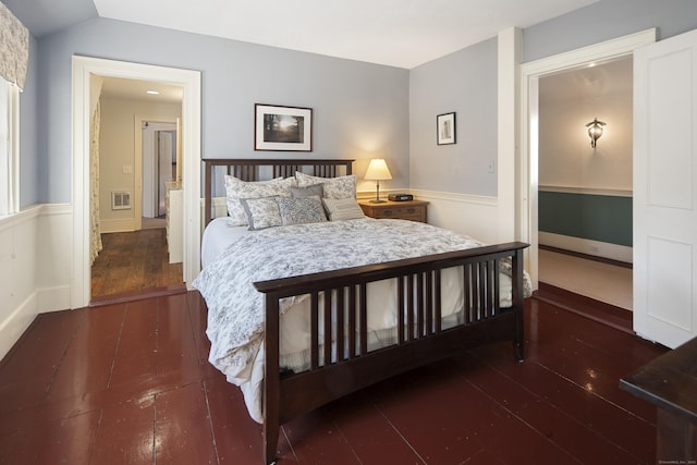 bedroom with hardwood / wood-style flooring, visible vents, and vaulted ceiling