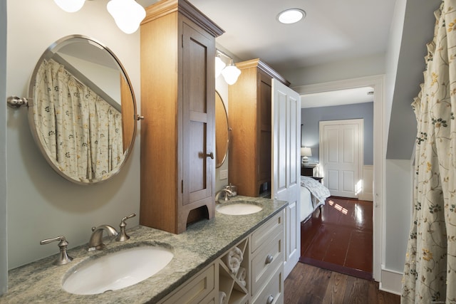 full bathroom with double vanity, ensuite bath, a sink, and wood finished floors