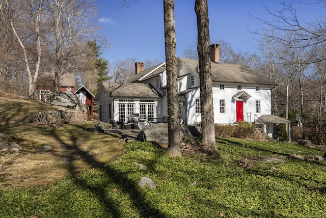 view of front facade with a chimney and a front yard