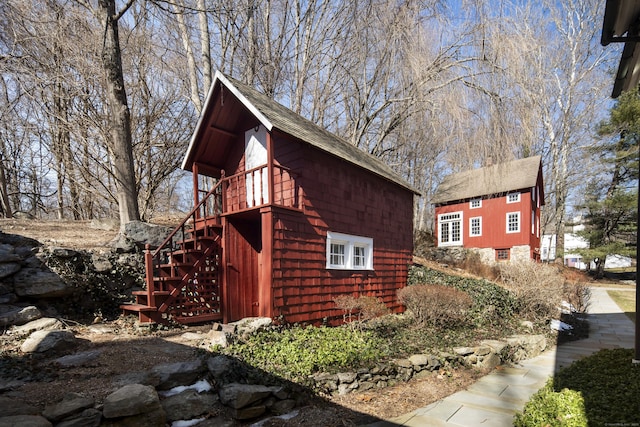 view of side of home featuring a shingled roof and stairway