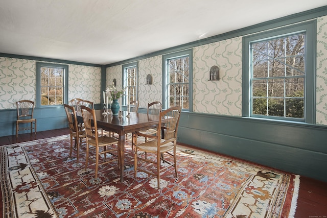 dining space with wood finished floors and wallpapered walls