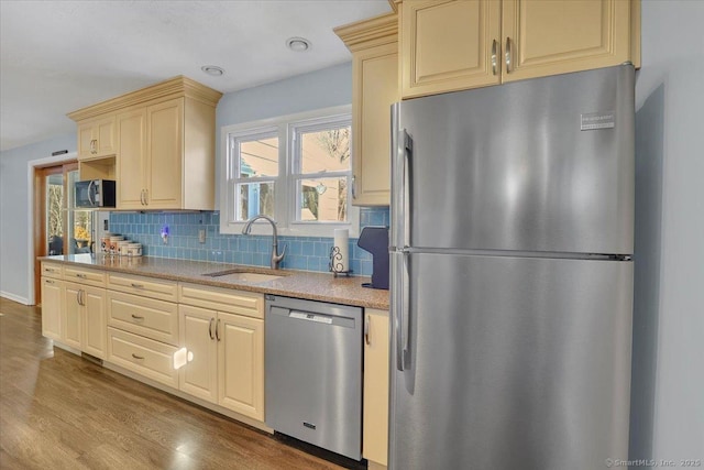 kitchen featuring backsplash, appliances with stainless steel finishes, sink, and light wood-type flooring