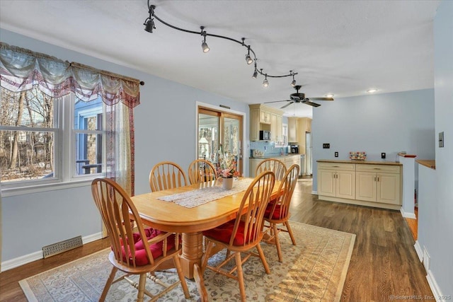 dining room with ceiling fan, rail lighting, and dark hardwood / wood-style flooring