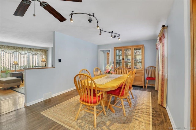 dining area with dark wood-type flooring and rail lighting