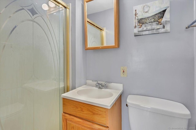 bathroom featuring a shower with door, vanity, and toilet