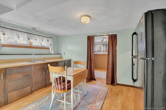 kitchen with black refrigerator, sink, and light hardwood / wood-style floors