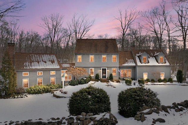 snow covered rear of property featuring a chimney