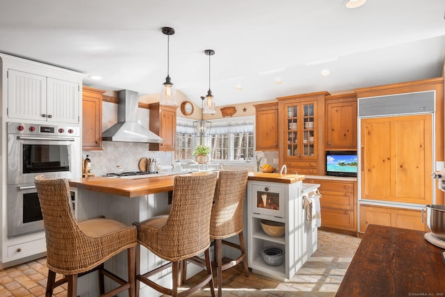 kitchen featuring stainless steel appliances, recessed lighting, backsplash, wall chimney range hood, and wood counters