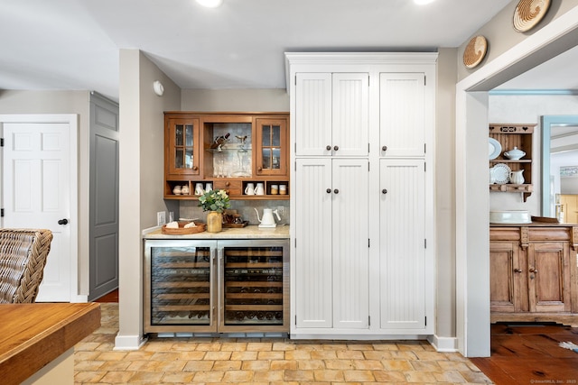 bar featuring tasteful backsplash, beverage cooler, baseboards, and a dry bar