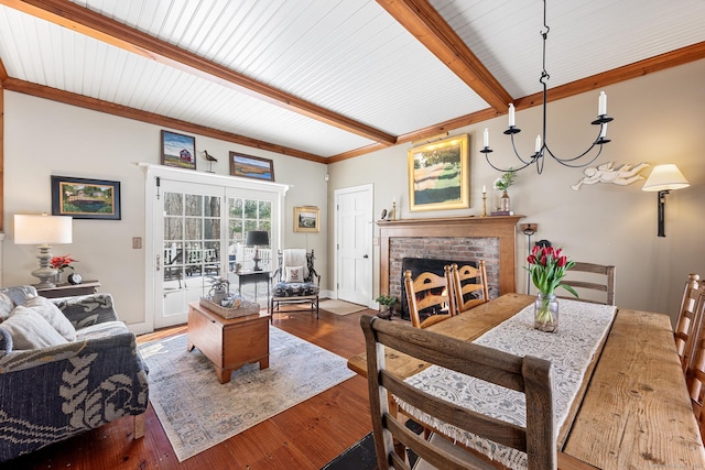 living area with a fireplace, beam ceiling, and wood finished floors