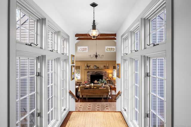 doorway with a chandelier, wood finished floors, a fireplace, high vaulted ceiling, and beam ceiling