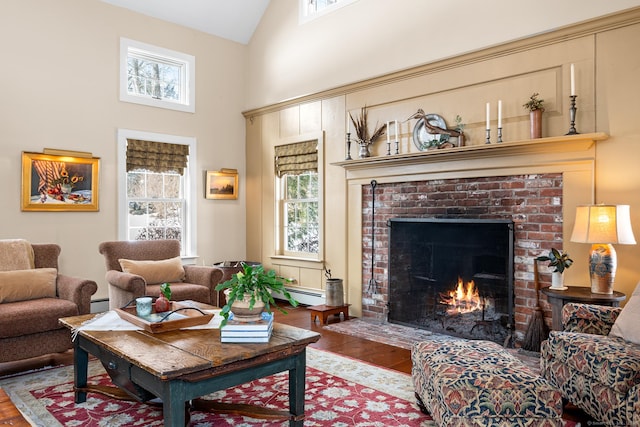 living room with a healthy amount of sunlight, a brick fireplace, high vaulted ceiling, and wood finished floors