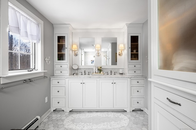 bathroom with crown molding, a baseboard radiator, a sink, and double vanity