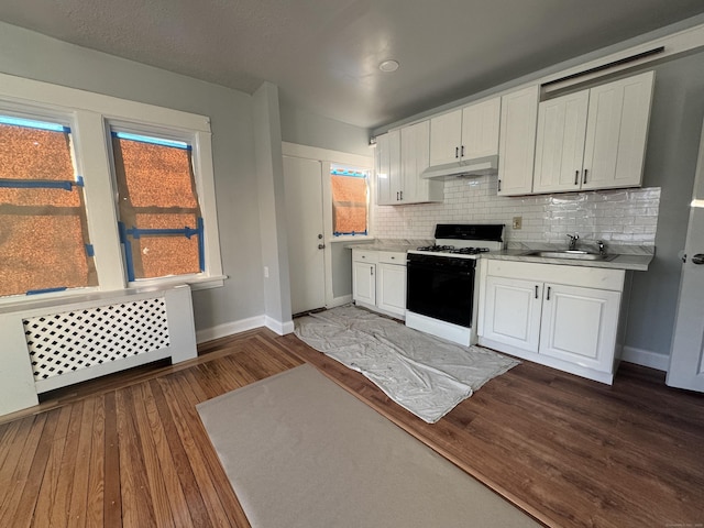 kitchen featuring sink, gas stove, white cabinetry, radiator, and backsplash