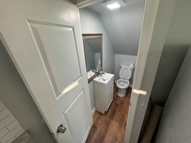 bathroom with vanity, hardwood / wood-style flooring, vaulted ceiling, and toilet