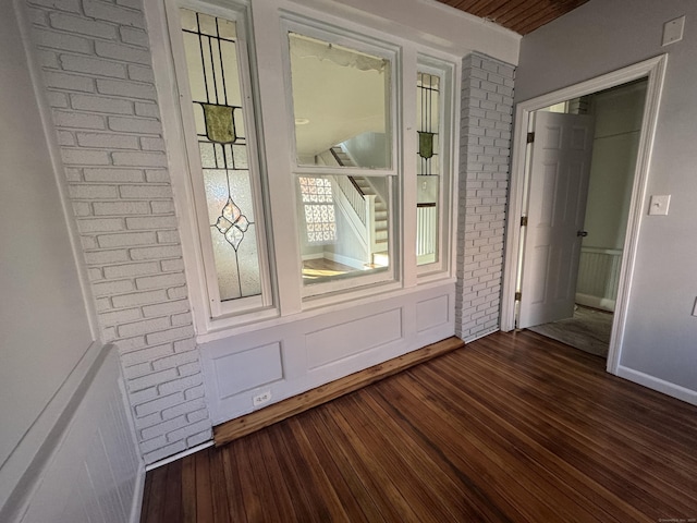 interior space featuring brick wall and dark wood-type flooring