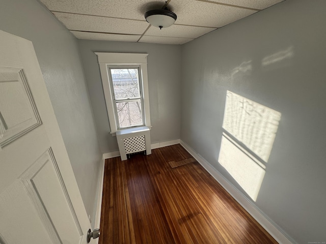 empty room with wood-type flooring and a drop ceiling