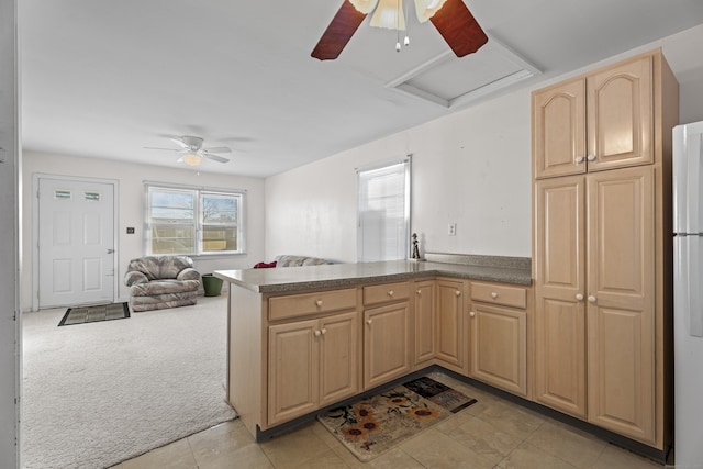 kitchen featuring light brown cabinetry, light carpet, white refrigerator, kitchen peninsula, and ceiling fan