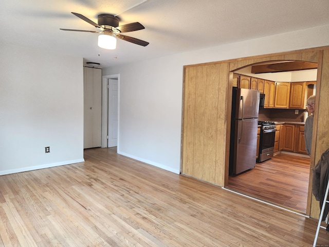 kitchen featuring stainless steel appliances, ceiling fan, and light hardwood / wood-style flooring