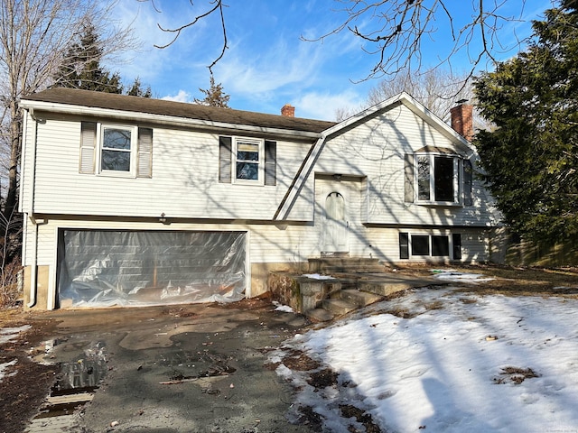 view of front of home with driveway, a garage, and a chimney