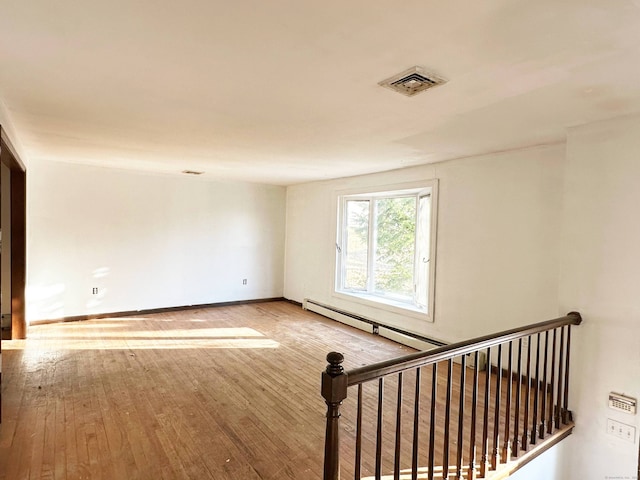 unfurnished room featuring a baseboard radiator, wood-type flooring, visible vents, and baseboards