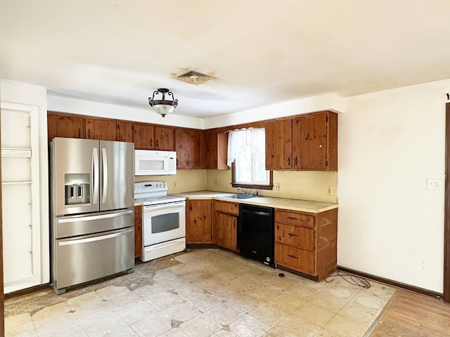 kitchen with white appliances, a sink, visible vents, light countertops, and light floors