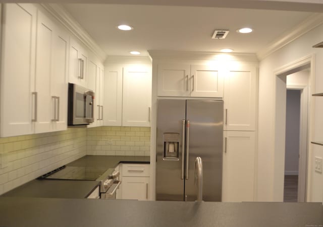 kitchen with white cabinetry, stainless steel appliances, crown molding, and backsplash