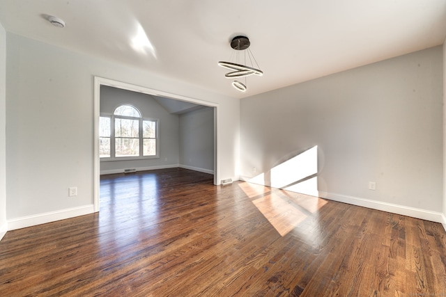 spare room featuring vaulted ceiling and dark hardwood / wood-style flooring