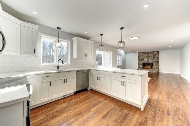 kitchen featuring pendant lighting, stainless steel dishwasher, kitchen peninsula, and white cabinets