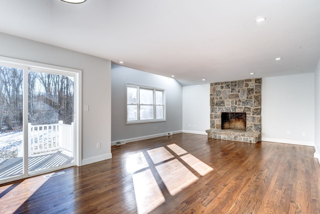 unfurnished living room with a stone fireplace and dark hardwood / wood-style floors