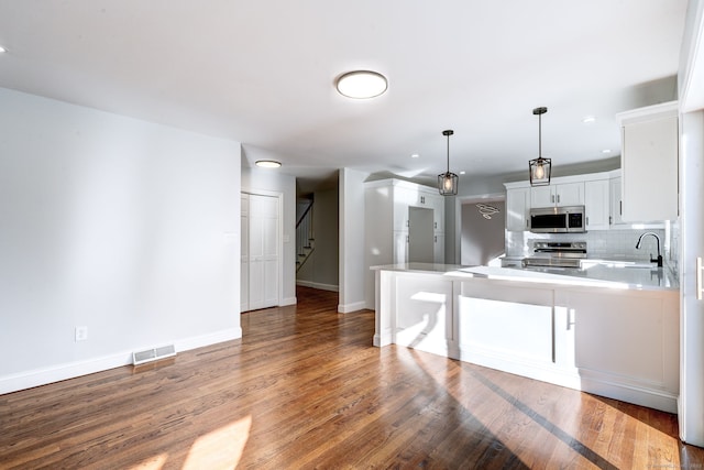 kitchen featuring decorative light fixtures, tasteful backsplash, white cabinetry, kitchen peninsula, and stainless steel appliances