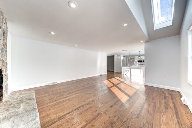 unfurnished living room featuring dark hardwood / wood-style flooring and a stone fireplace