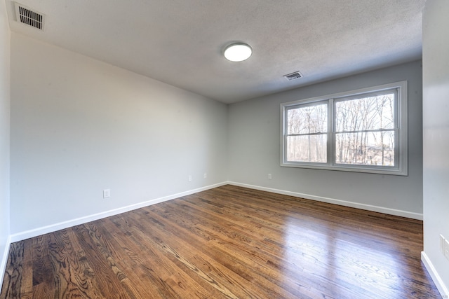 spare room with dark wood-type flooring and a textured ceiling