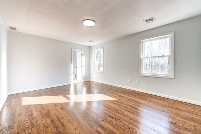 empty room with hardwood / wood-style flooring and a textured ceiling